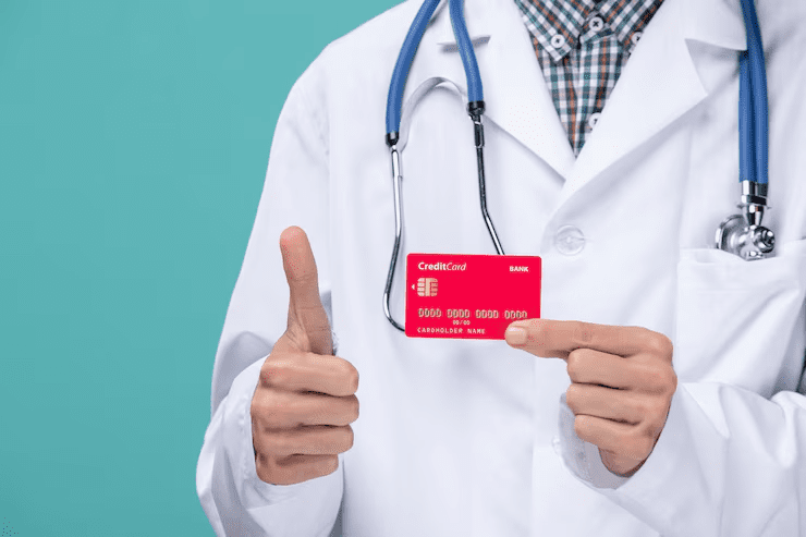Doctor in a white lab coat with a stethoscope showing a red medical credit card and giving a thumbs-up, symbolizing healthcare financing or medical credit card approval.