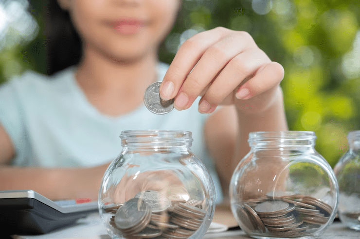 Young woman placing coins into a glass jar filled with change, representing personal finance habits, budgeting, or saving money concept.