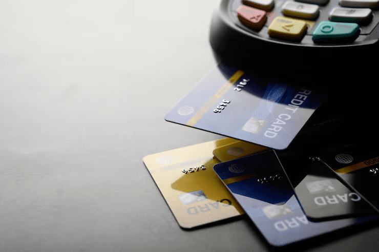 Close-up of multiple colorful credit cards near a payment terminal, highlighting the concept of credit card payment and digital transactions on a dark surface.