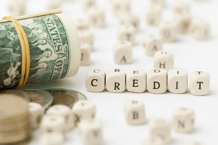 "Rolled U.S. dollar bills and coins next to lettered cubes spelling 'CREDIT', symbolizing financial credit or lending."