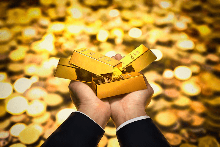 "Person in a suit holding multiple gold bars in their hands, with a blurred background of glowing gold coins, symbolizing wealth, investment, or gold assets."