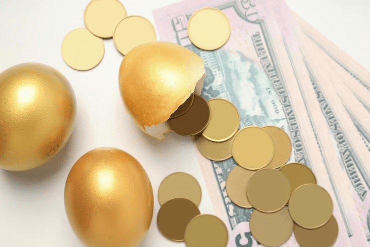 Golden eggs with one cracked open, spilling out gold coins, placed over U.S. dollar bills—symbolizing financial growth, investment returns, and wealth accumulation.