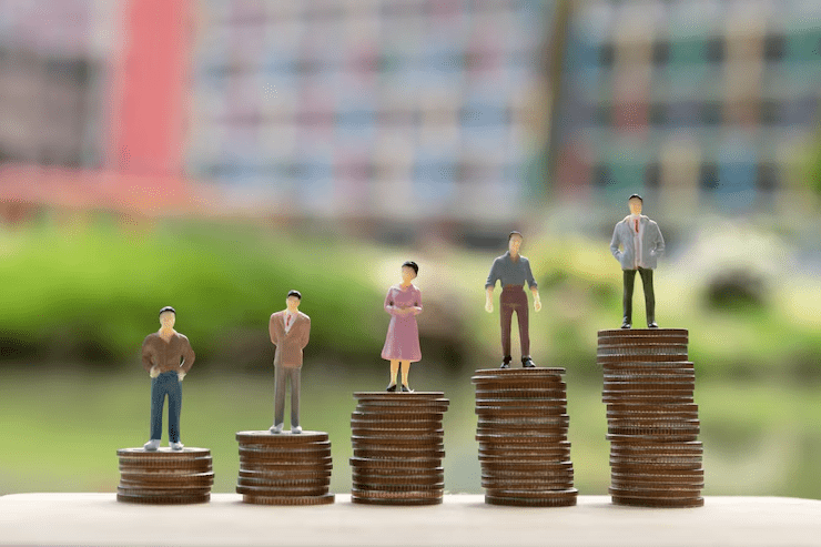 Miniature figurines of people standing on stacks of coins arranged in ascending order, symbolizing income levels, wealth growth, or financial inequality.