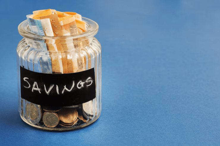 Glass jar labeled "SAVINGS" filled with coins and euro banknotes, symbolizing personal savings or financial planning.