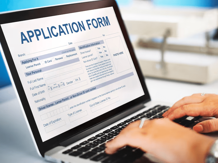 Person filling out an online application form on a laptop, representing digital form submission for services like credit cards, loans, or banking registration.